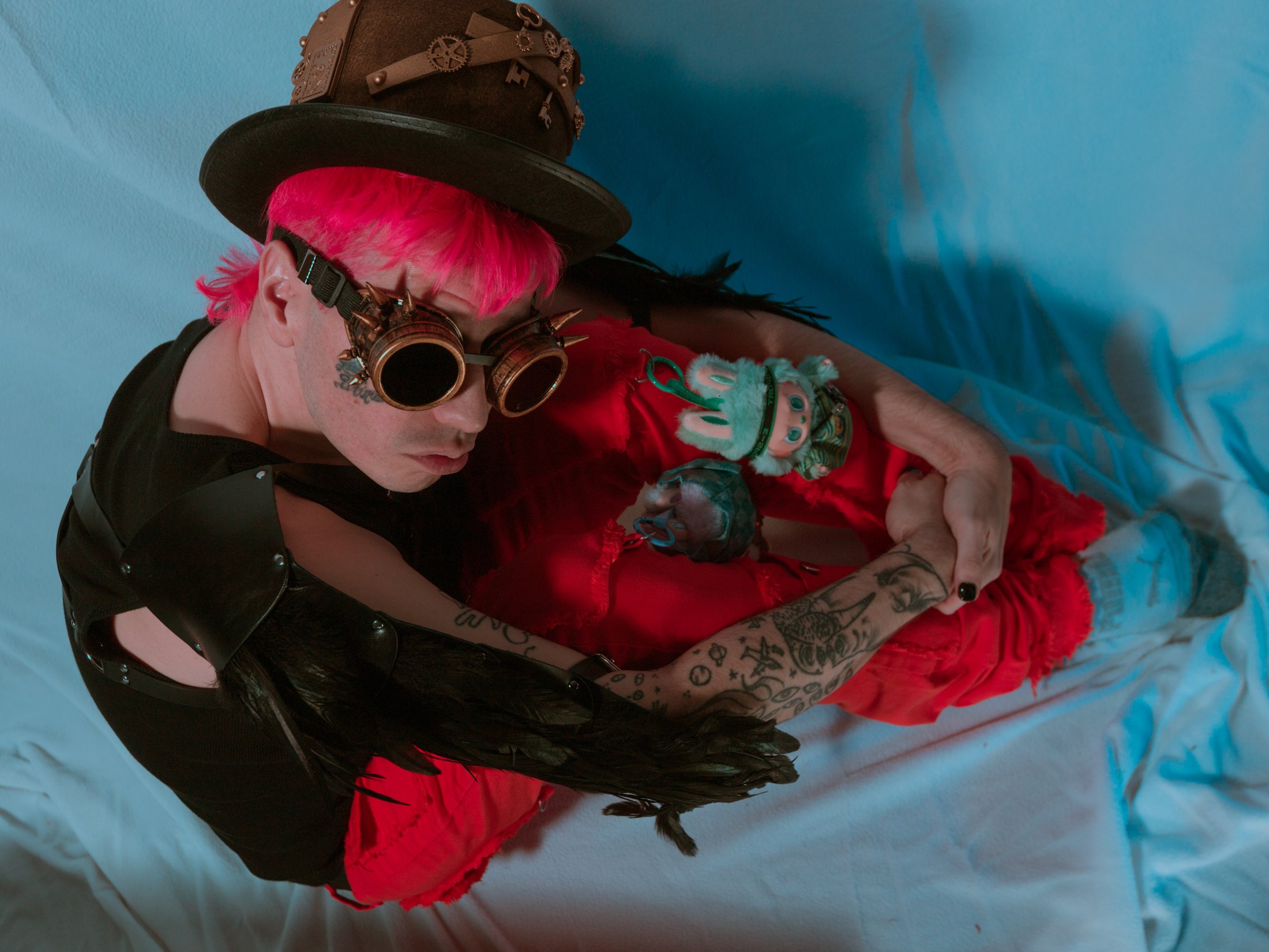 Editorial press photo of Lord Infinit3 with hot pink hair, goggles, and a red character costume