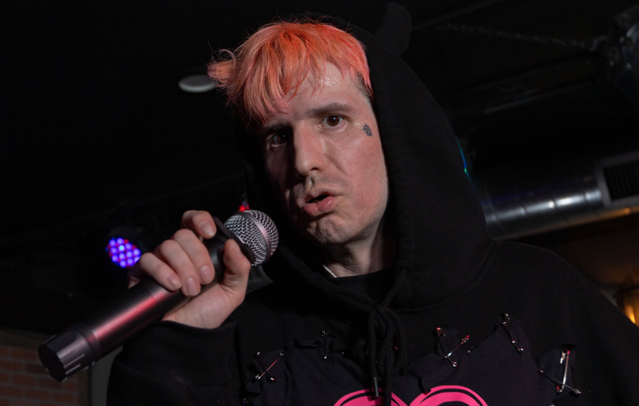 Close-up live press photo of Lord Infinit3 performing into a microphone